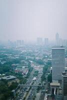 High-rise buildings and a major road in Jakarta city, with visible air pollution creating a hazy urban atmosphere photo