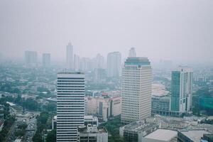 High-rise buildings and a major road in Jakarta city, with visible air pollution creating a hazy urban atmosphere photo
