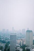High-rise buildings and a major road in Jakarta city, with visible air pollution creating a hazy urban atmosphere photo