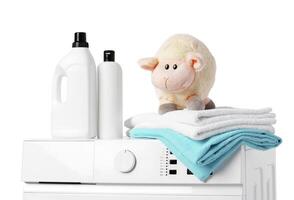 Laundry Detergent Bottles, Sheep Toy, and Towels on Top of a White Washing Machine photo