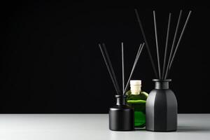 Two Black Reed Diffuser Bottles on a White Surface With Grey Background photo