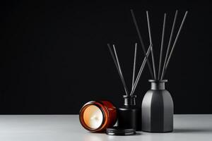 Black Reed Diffuser and Candle on Grey Surface Against Black Background photo