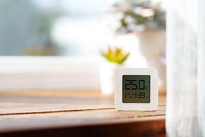 Digital Thermometer Displaying Temperature and Humidity Near Window photo