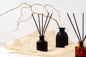 Black Glass Diffuser Bottles With Reed Sticks and Dried Twigs on Cream Paper photo