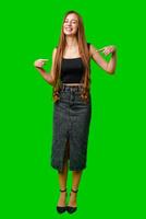 Young Woman Smiling and Pointing at Herself in Front of a Green Screen photo