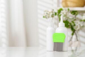 Bottles of Lice Treatment Products and a Comb on a Countertop photo