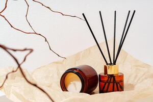Brown Glass Reed Diffuser and Candle on White Background With Branch photo