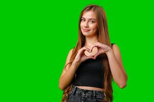 Young Woman Making Heart Shape With Hands on Green Screen photo