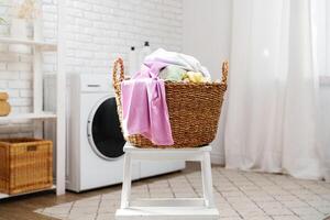 Laundry Basket With Clean Clothes Sitting on White Stool in Laundry Room photo