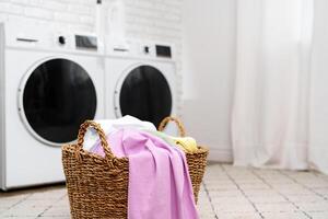 Laundry Basket With Clean Clothes in Front of Modern Washing Machines photo