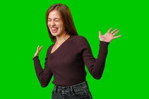 Young Woman in Brown Sweater Laughing and Gesturing Against a Green Screen photo