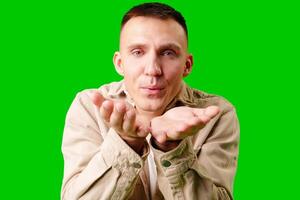 Young Man Making Playful Gesture With Open Hands Against Bright Green Background photo