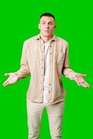 Confused Young Man Standing Against Bright Green Background With Open Arms in Uncertain Gesture photo