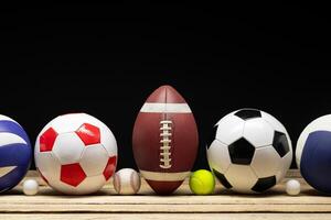 Set of various sport balls on wooden floor on black background photo