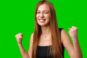 Happy Woman With Long Brown Hair Celebrating With Fists Raised In Front of Green Screen photo