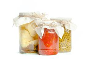 Canned vegetables in glass jars isolated on white background photo