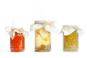 Canned vegetables in glass jars isolated on white background photo