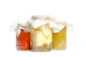 Canned vegetables in glass jars isolated on white background photo