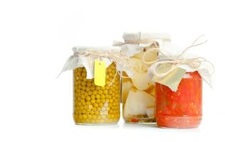 Canned vegetables in glass jars isolated on white background photo