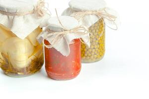 Canned vegetables in glass jars isolated on white background photo