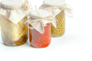 Canned vegetables in glass jars isolated on white background photo