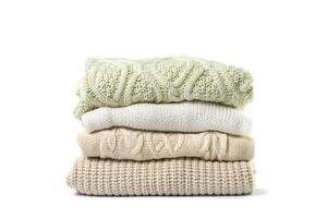 Stack of various sweaters isolated on white background photo