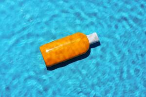 Sunscreen bottle floating in a clear blue swimming pool on a sunny day photo
