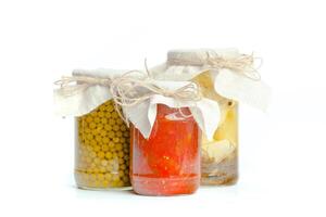 Canned vegetables in glass jars isolated on white background photo
