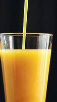 Close-up view of orange juice in a clear glass against a dark background video