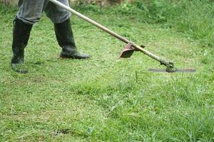 Close up man is using mowing machine to mow the lawn in his garden. Concept , using agricultural machine instead of using herbicide or chemical to get rid of weeds. Eco friendly gardening. photo