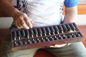 Close up man hand calculate and count wooden abacus. Concept, ancient style calculation. Counting equipment. Calculator. Educational material. Math teaching aid photo