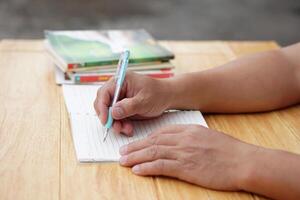 Close up hand use pen to write on paper notebook. Concept, Education. Reading and summarizing by writing idea or knowledge. Learning style. Doing homework. Prepare for test. Taking notes. photo