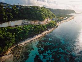 Hidden beach under cliffs with road. Coastline and ocean with sunshine in Bali island. Drone view photo