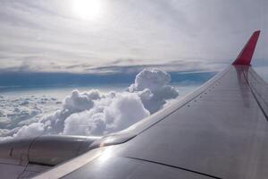 Airplane wing flying on clouds in sky photo