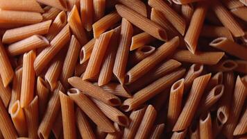 Uncooked Whole Grain Penne Rigate Pasta. A Culinary Canvas of Whole Wheat Macaroni, Textured Background - Top View, Rotating. Turning Whole Grain Dry Pasta. Whole Wheat Raw Macaroni - Rotation video