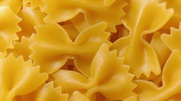 Uncooked Farfalle Pasta. A Culinary Canvas of Bow-Tie Macaroni, Creating a Lively and Textured Background for Gourmet Cooking - Top View, Rotating. Turning Dry Pasta. Raw Macaroni - Rotation video