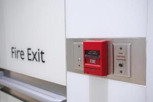 Red fire alarm and exit sign in building corridor photo