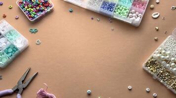 Crafting with colorful beads on a flat workspace with tools and containers in bright daylight video