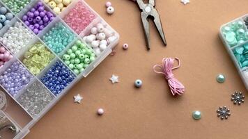 Crafting with colorful beads on a flat workspace with tools and containers in bright daylight video