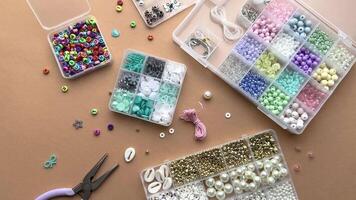 Crafting with colorful beads on a flat workspace with tools and containers in bright daylight video