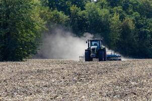 The tractor drives the field. An agricultural tractor on the cultivation of a farm field. Tractor disc harrow plows a farmer's field. Agronomy and the agricultural sector. photo