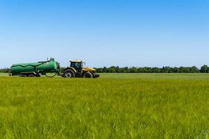 A tractor carries a barrel of liquid from pests across the field photo