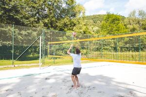 Volleyball player setting the ball on a sand court, preparing for the next play during an outdoor beach volleyball game. The action highlights control and precision in the game photo