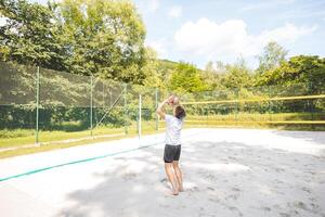 Volleyball player setting the ball on a sand court, preparing for the next play during an outdoor beach volleyball game. The action highlights control and precision in the game photo