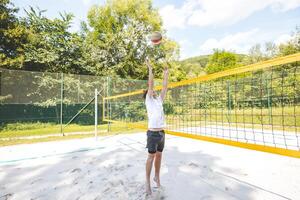 Volleyball player setting the ball on a sand court, preparing for the next play during an outdoor beach volleyball game. The action highlights control and precision in the game photo