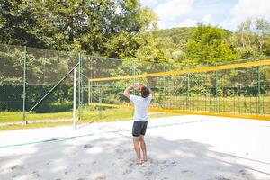 Volleyball player setting the ball on a sand court, preparing for the next play during an outdoor beach volleyball game. The action highlights control and precision in the game photo