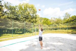 Volleyball player setting the ball on a sand court, preparing for the next play during an outdoor beach volleyball game. The action highlights control and precision in the game photo