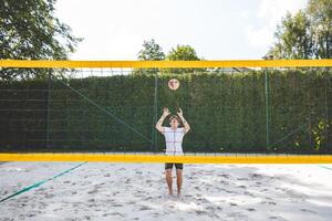 Volleyball player setting the ball on a sand court, preparing for the next play during an outdoor beach volleyball game. The action highlights control and precision in the game photo