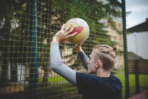 Volleyball player preparing to set the ball near the net on a hard court, focusing on precision and control. Captured from behind, showcasing outdoor volleyball skills photo