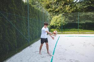 Volleyball player practicing a bump pass on a sand court, focusing on technique and control. Captured in an outdoor setting, showcasing beach volleyball skills and training photo